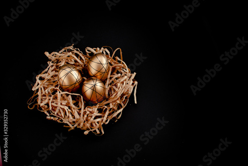 Easter goldenand white decorated eggs in nest on black background . Minimal easter concept copy space for text. Top horizontal view photo