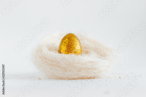 Easter golden decorated eggs in nest on white background . Minimal easter concept copy space for text.