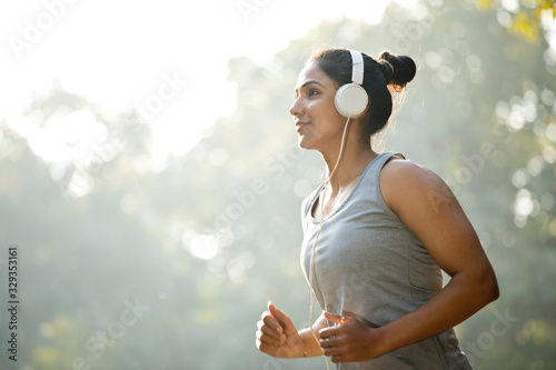 Sportswoman listening music and jogging at park