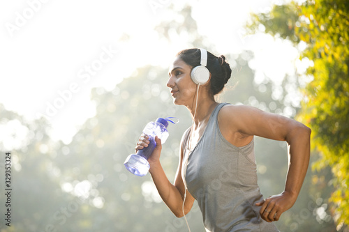 Woman in sportswear listening music while exercising at park outdoor