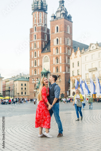 a young couple is stylishly dressed, a girl in a red dress, a man in a blue shirt and blue pants, walk the streets in Krakow Poland © Alexander