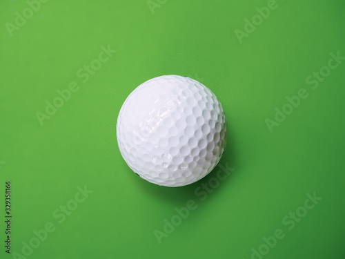 Top view of golf ball on green background.