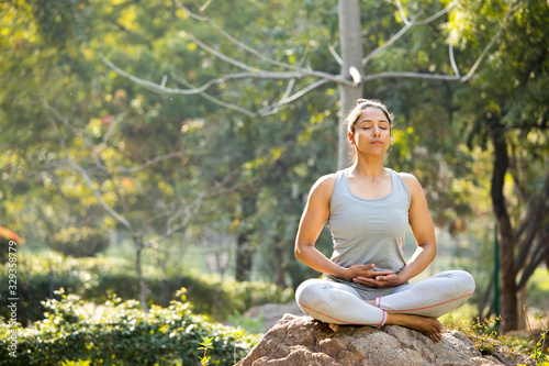 Woman practicing yoga in lotus position at park