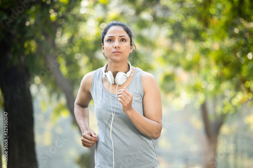 Sportswoman listening music and jogging at park