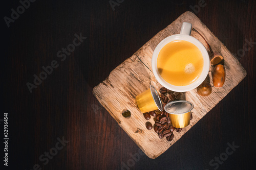 Cup of coffee in woodden background with coffee capusles ands coffee beans