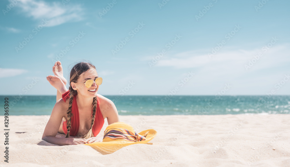 Woman enjoying her vacation by the sea tanning in the beach sand - obrazy, fototapety, plakaty 