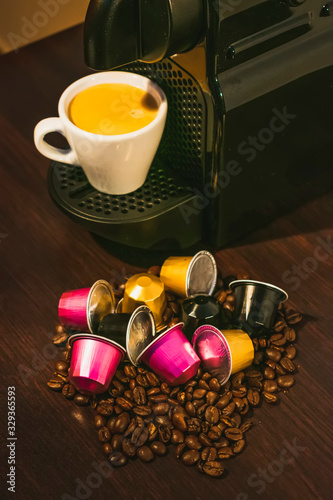 Cup of coffee amd coffee machine in woodden background with coffee capusles ands coffee beans