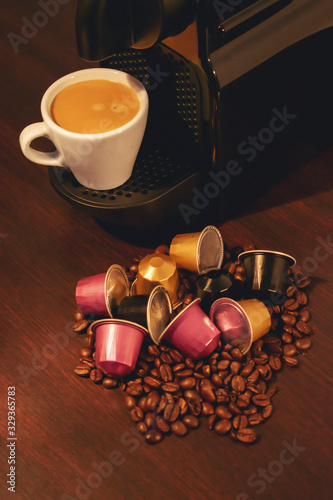 Cup of coffee amd coffee machine in woodden background with coffee capusles ands coffee beans