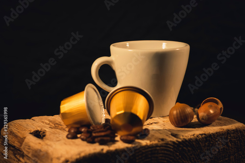 Cup of coffee in woodden background with coffee capusles ands coffee beans