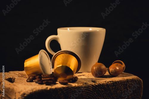 Cup of coffee in woodden background with coffee capusles ands coffee beans