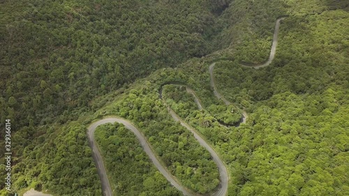 Aerial overhead shot over a lonely serpentine road at Egmont National Park, North Island, New Zealand. It's a sunny day with a few clouds. photo