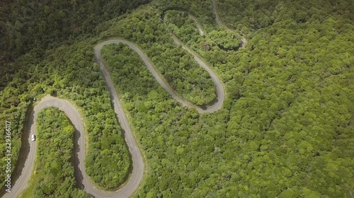 Aerial overhead shot over a lonely serpentine road at Egmont National Park, North Island, New Zealand. It's a sunny day with a few clouds. photo