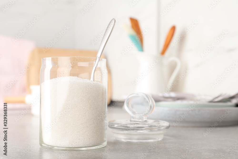Jar with white sugar on grey table