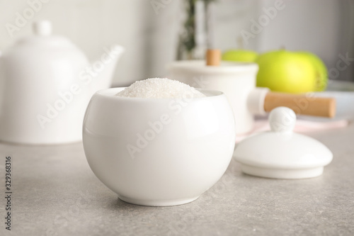 Ceramic bowl with white sugar on grey table