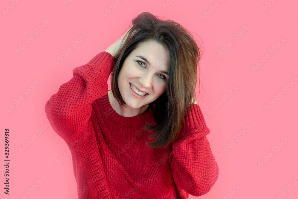 Portrait of an attractive brunette girl with green eyes in a red sweater on a pink background. Studio photo Portrait of an attractive brunette girl with green eyes in a red sweater on a pink background. Studio photo
