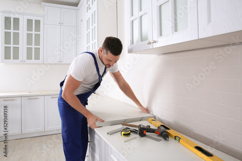 Worker installing new countertop in modern kitchen photo