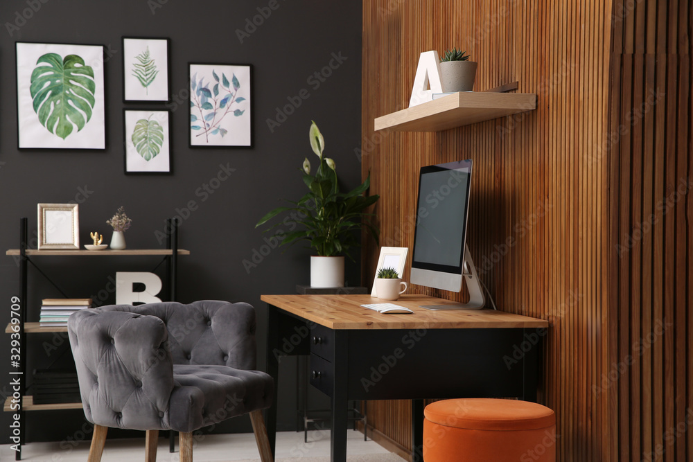 Comfortable workplace with computer near wooden wall in stylish room interior. Home office design Comfortable workplace with computer near wooden wall in stylish room interior. Home office design