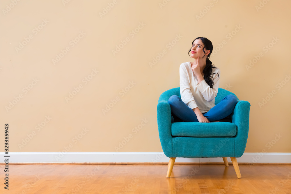 Young woman in a thoughtful pose sitting in a chair Young woman in a thoughtful pose sitting in a chair