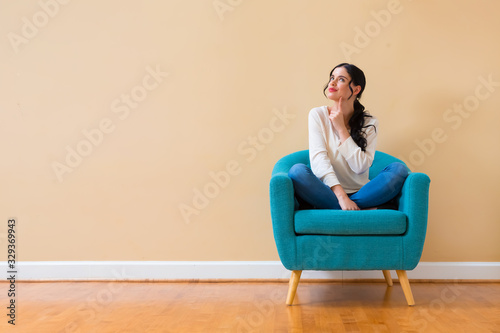 Young woman in a thoughtful pose sitting in a chair