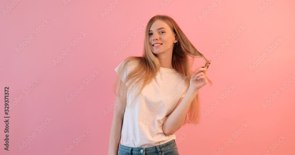 Pensive positive girl in a white t-shirt with a smile looks away, on a pink background Pensive positive girl in a white t-shirt with a smile looks away, on a pink background