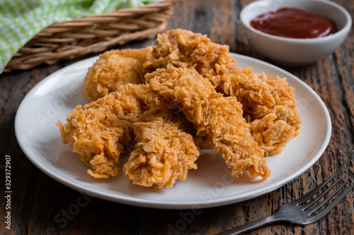 Crispy fried breaded chicken strips on plate and ketchup.