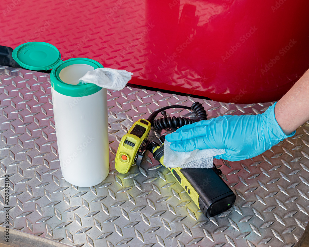 Firefighter cleaning portable radio equipment with disinfectant wipe ...