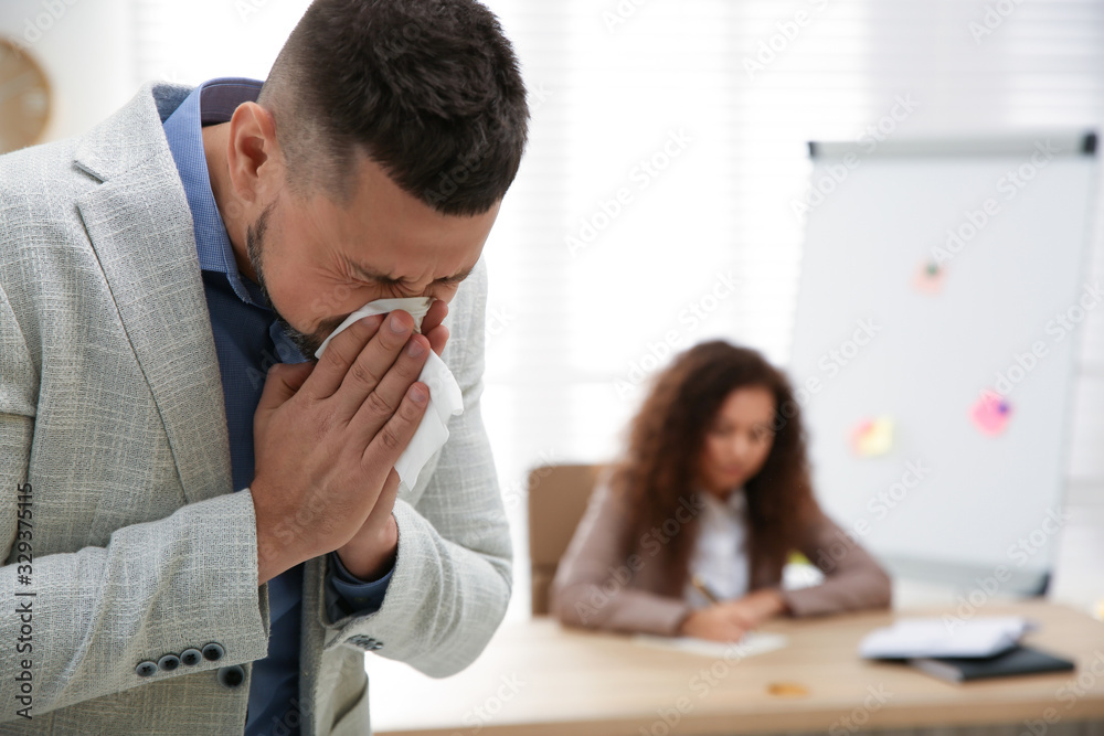 Sick man sneezing in office. Influenza virus Sick man sneezing in office. Influenza virus
