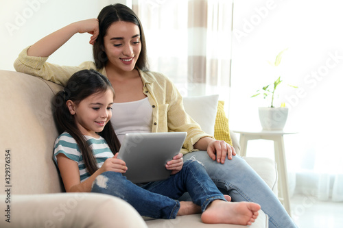 Mother and daughter reading E-book together at home