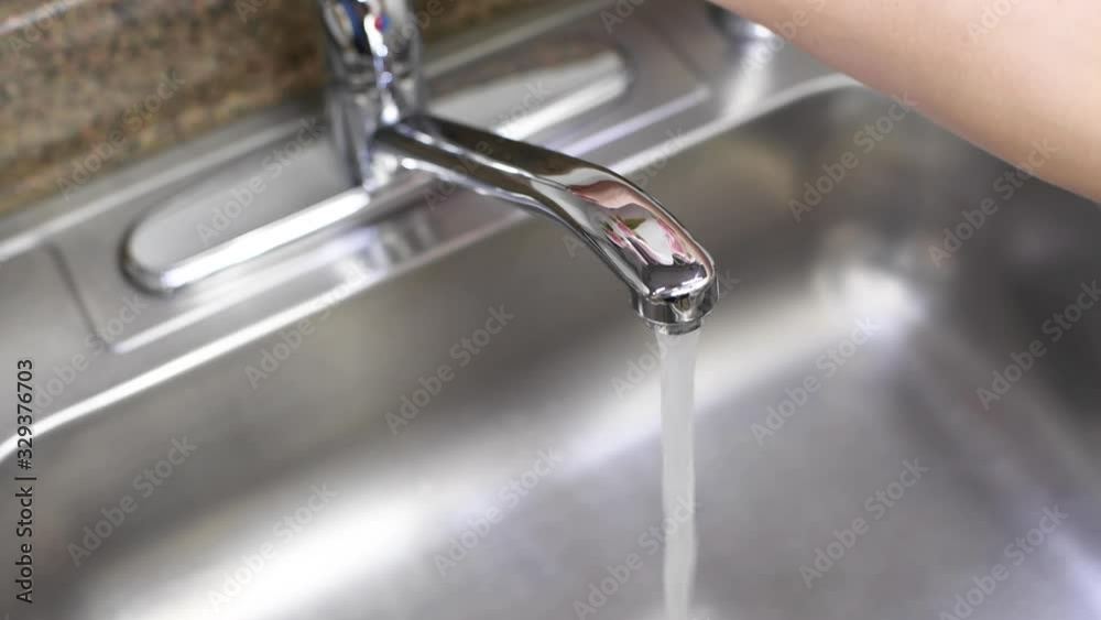 Water flowing in wash sink, then woman's hand turns off a water faucet Water flowing in wash sink, then woman's hand turns off a water faucet
