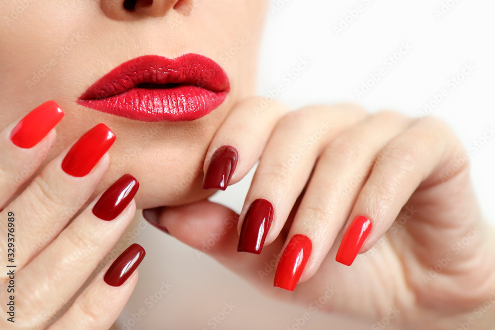Naklejka premium Fashionable makeup and manicure in dark red and light shades of nail Polish.Creative nail art on a young girl on a white background.