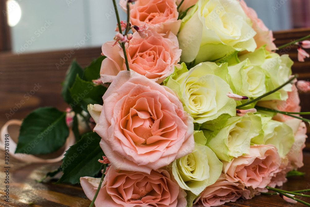 Obraz premium Elegant wedding bouquet of white and pink roses lying on the brown wooden table
