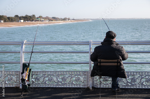 a man sitting on a pier fishing with a fishing rod