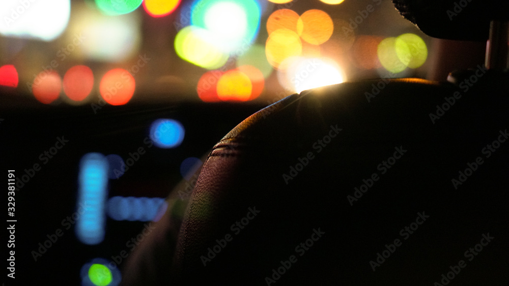 Colorful traffic light at night blur background view from car interior behind leather seat view