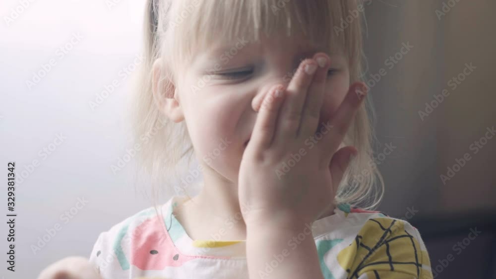 a little girl with blond hair tastes a slice of lemon. sour lemon. vitamin C is useful for children
