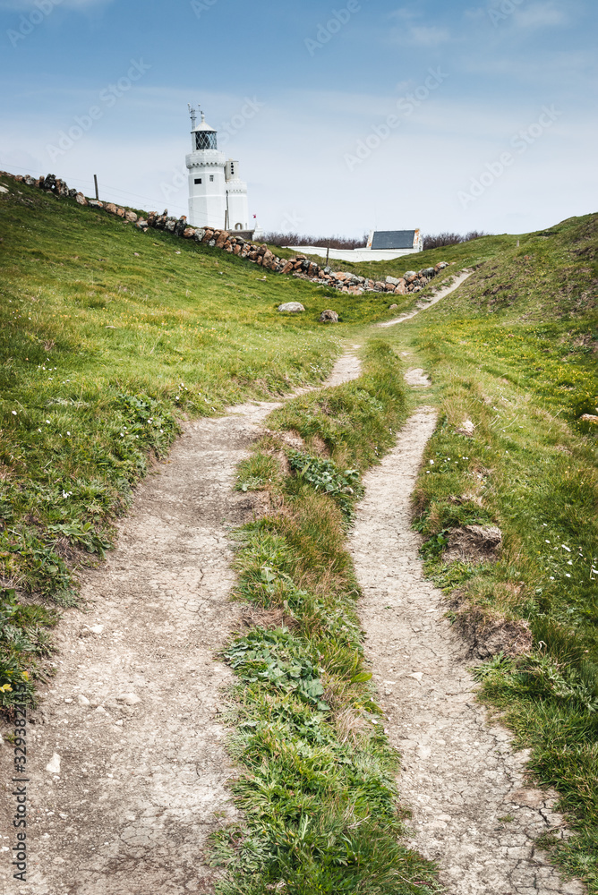 a country track leading to a white lighthouse
