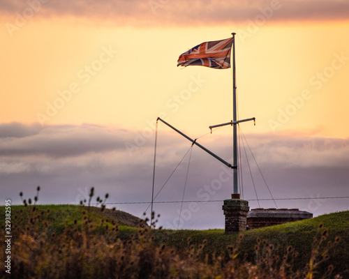 a union jack flag or British flag flying on a flagpole at sunset