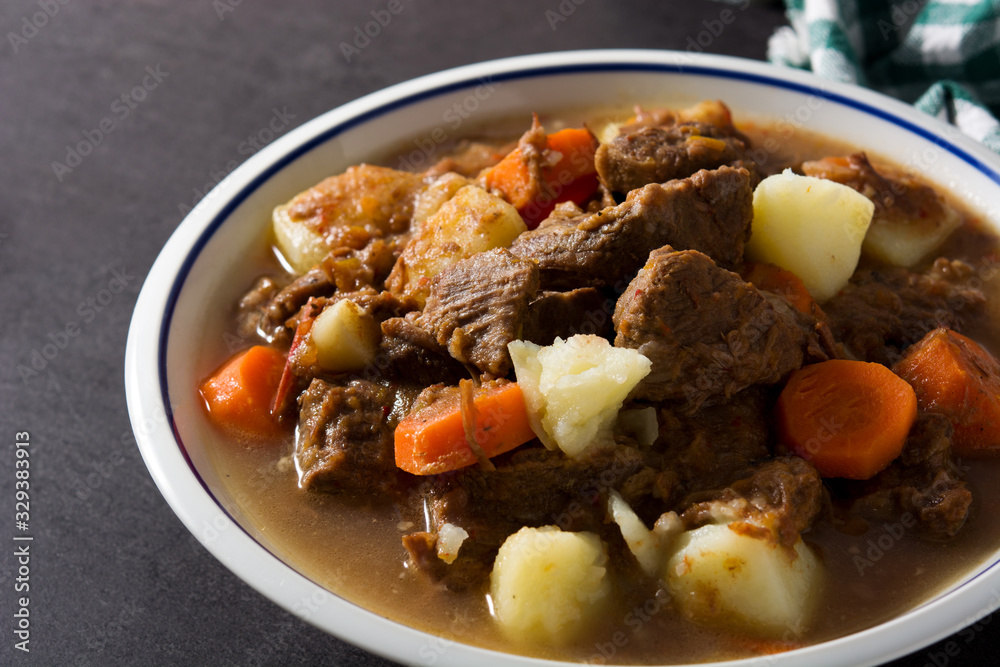 Irish beef stew with carrots and potatoes on black background Irish beef stew with carrots and potatoes on black background