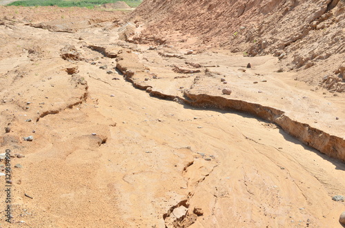 Background of yellow sand with small stones after rain. Soil erosion after heavy rainfall and precipitation. Texture of scattered sand fine gravel