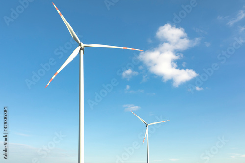 wind turbines in green field, countryside area with blue sky