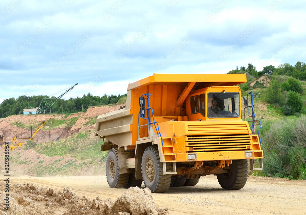 Big yellow mining truck working in the limestone open-pit. Loading and transportation of minerals in the dolomite mining quarry. Belarus, Vitebsk, in the largest dolomite deposit, quarry 