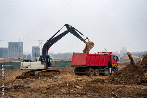 Excavator load the sand to the heavy dump truck on construction site.