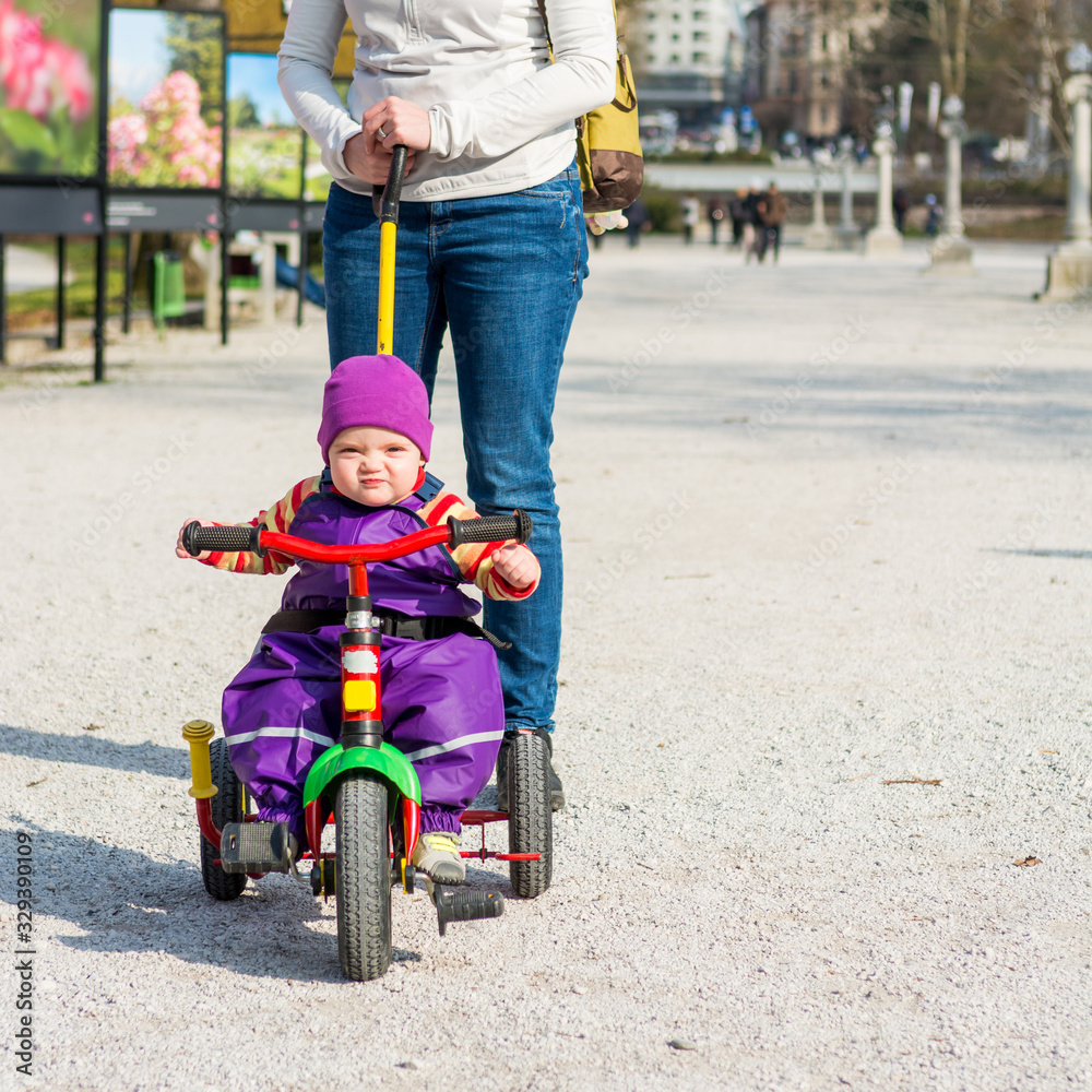 Cute baby girl enjoying her first bycicle ride with mothers help. Cute baby girl enjoying her first bycicle ride with mothers help.