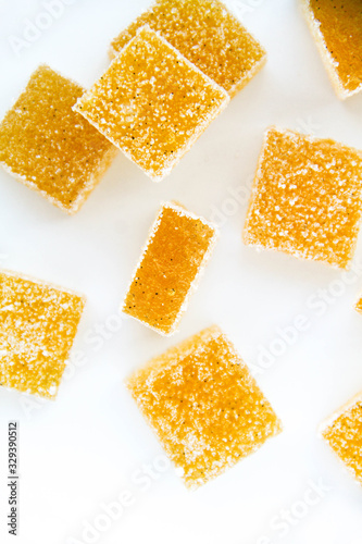 Pineapple, lemon, vanilla pate de fruit (jelly, marmalade, fruit candy) covered with sugar. White background, top view. There are sliced jellies on a photo to show a texture inside of pate de fruit.