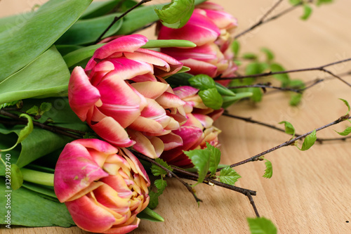 Bright spring bouquet of colorful tulips and blossoming branches of a birch lying on the light table.Present concept for Birthday  mother s Day and Easter