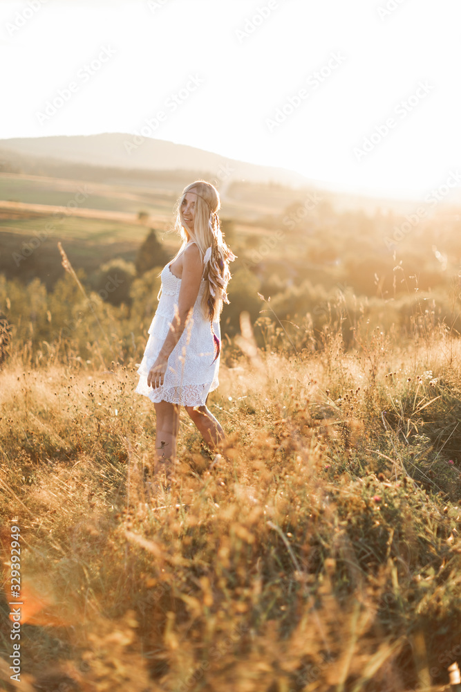 Beautiful young boho hippie girl in white dress at sunset, smiling and having fun. Feathers in hair, bohemia boho style Beautiful young boho hippie girl in white dress at sunset, smiling and having fun. Feathers in hair, bohemia boho style