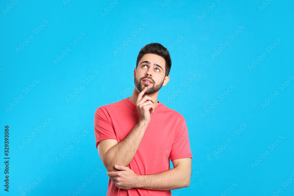 Pensive young man on light blue background. Thinking about difficult question Pensive young man on light blue background. Thinking about difficult question