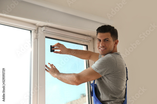 Professional worker tinting window with foil indoors