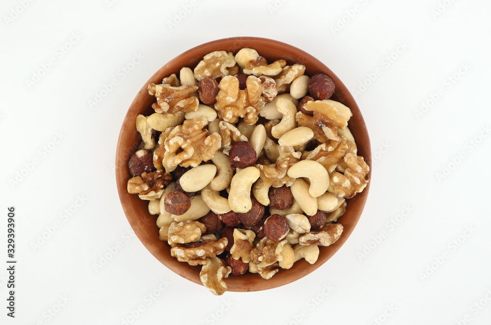 Mixture of peeled nuts made of walnuts,hazelnuts,almonds and cashews ina terracotta bowl. White background. Mixture of peeled nuts made of walnuts,hazelnuts,almonds and cashews ina terracotta bowl. White background.