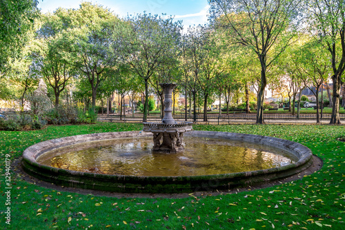 A small scenic antique fountain in the park near the Army Museum at Les Invalides complex, Paris, France