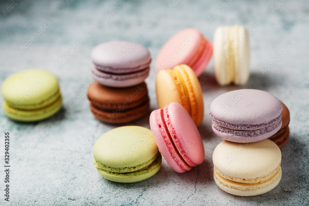 Multicolored macaroni cookies lie on a gray stone slab. Multicolored macaroni cookies lie on a gray stone slab.